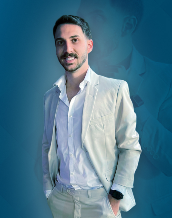 Homem sorridente em traje claro posando sobre fundo azul, transmitindo confiança e estilo. Uma imagem que destaca sofisticação e elegância.